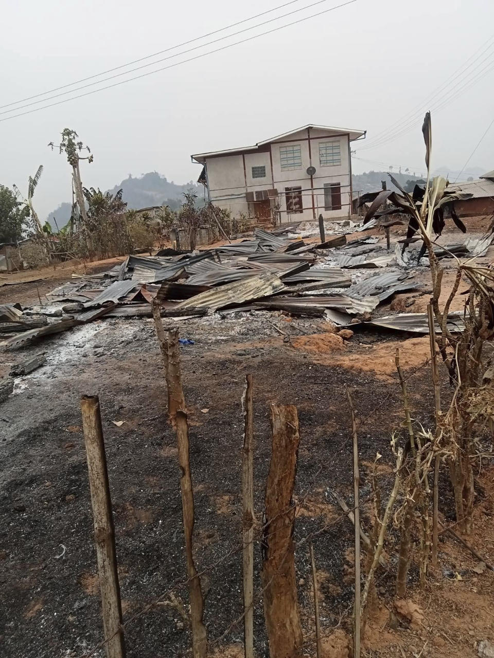 In this image provided by the Karenni Nationalities Defense Force, burnt corrugated roofing and debris can be seen on the ground in Nam Nein village, Pinlaung township in Shan state, Myanmar on Sunday, March 12, 2023. Myanmar's military government has denied reports of a new mass killing of civilians by its troops, instead blaming pro-democracy resistance groups for the deaths of more than 20 people. (Karenni Nationalities Defense Forcevia AP)