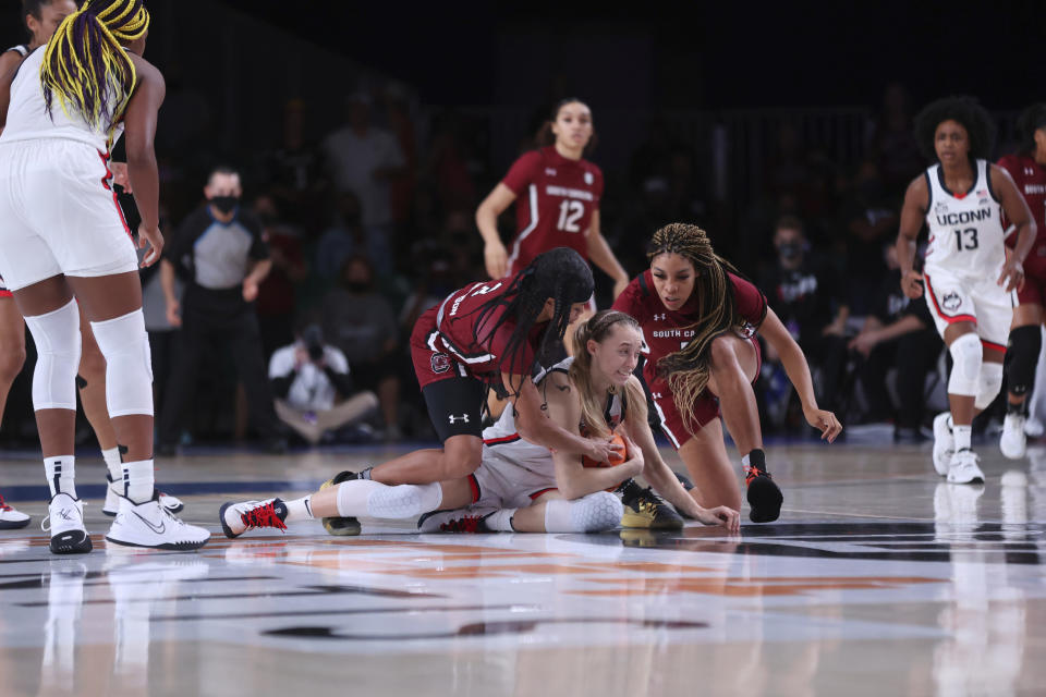 In this photo provided by Bahamas Visual Services, South Carolina forward Victaria Saxton (5), right, guard Destanni Henderson (3), left, and UConn guard Paige Bueckers (5), foreground, fight for ball possession during an NCAA college basketball game at Paradise Island, Bahamas, Monday, Nov. 22, 2021. (Tim Aylen/Bahamas Visual Services via AP)