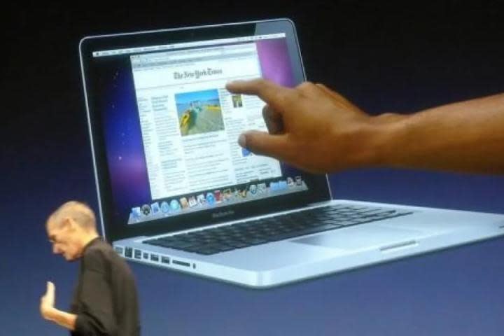 Steve Jobs in front of a graphic of a touchscreen MacBook.