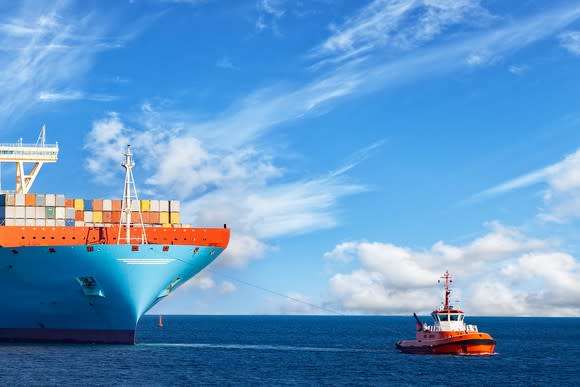 A tug boat pulling a shipping vessel into port.