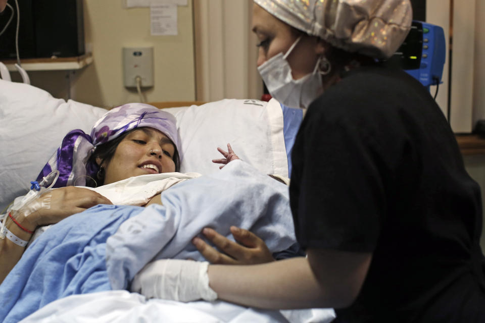 A midwife tends to Angela Quintana Aucapan and her newborn son, Namunkura, at the San Jose de Osorno Base Hospital in Osorno, Chile, Saturday, Aug. 20, 2022. Reclaiming ancestral practices is what drew Quintana Aucapan to have her baby in the special delivery room recently. (AP Photo/Luis Hidalgo)