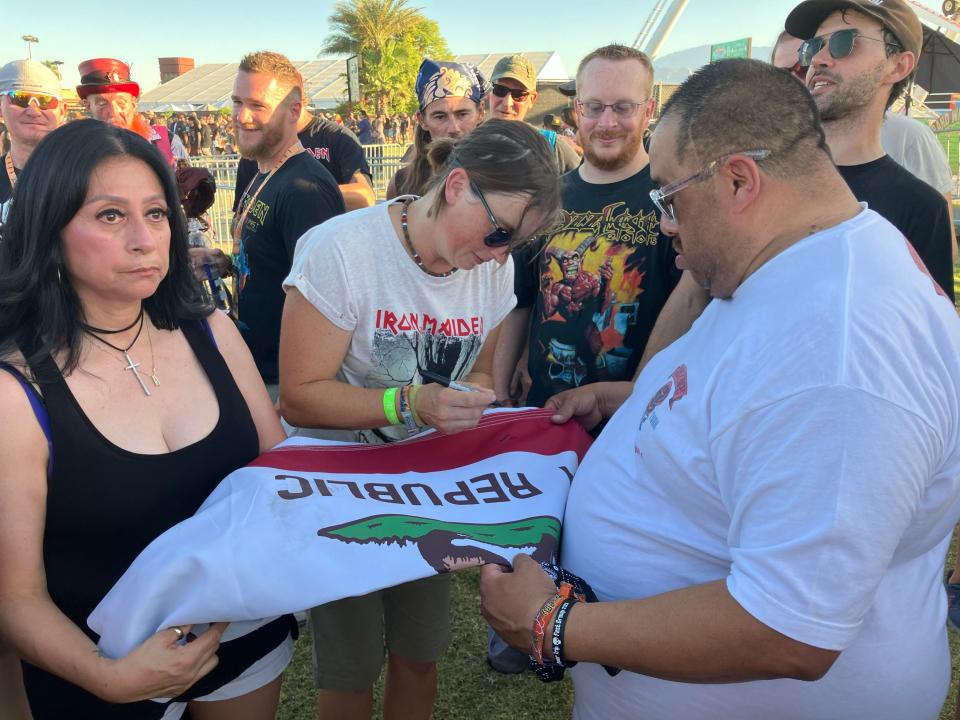 A member of the Facebook community Power Trip Festival Group has members sign a California state flag during the Power Trip festival at the Empire Polo Club in Indio, Calif., on Oct. 6, 2023.