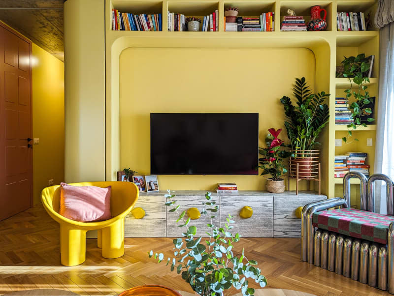 Yellow living room with built in bookshelves, parquet floors, and unique rounded furniture