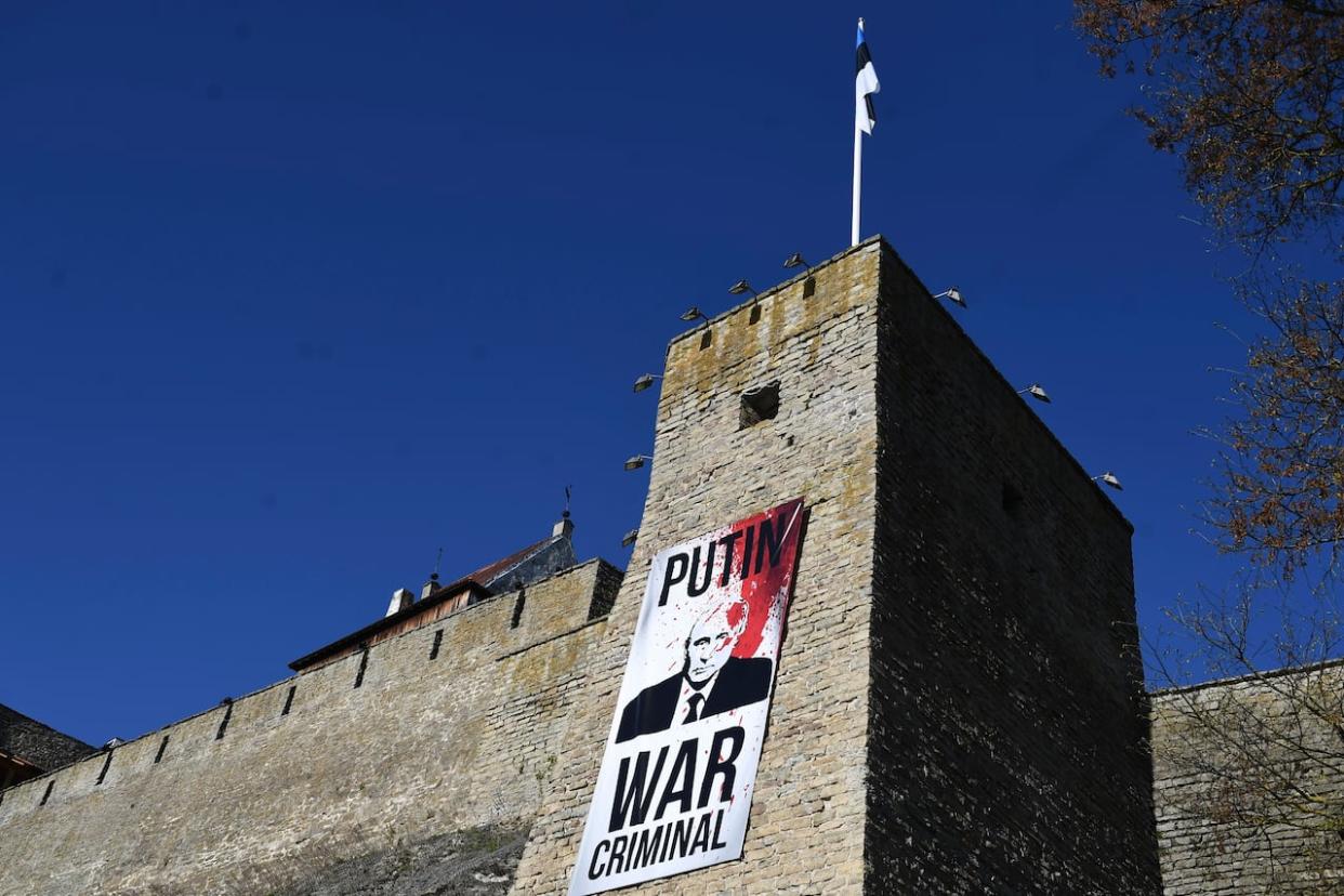 A poster with an image of Russian President Vladimir Putin on the wall of the Narva Castle opposite the Russian border in Narva, Estonia on Tuesday, May 9, 2023. (Associated Press - image credit)