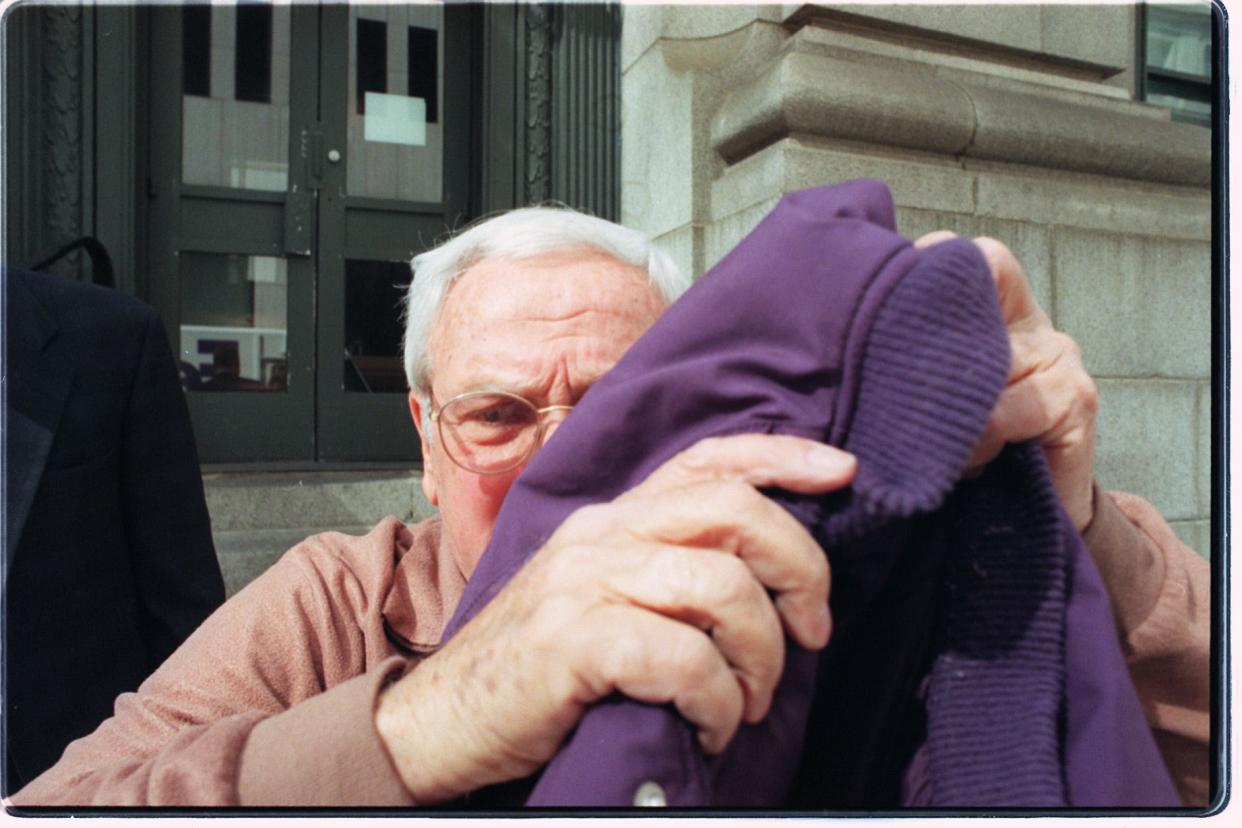 Joseph Pannone, chairman of Providence's tax assessment review board, tries to hide under a coat while exiting the federal courthouse after being indicted on charges of laundering money paid as bribes for tax breaks.