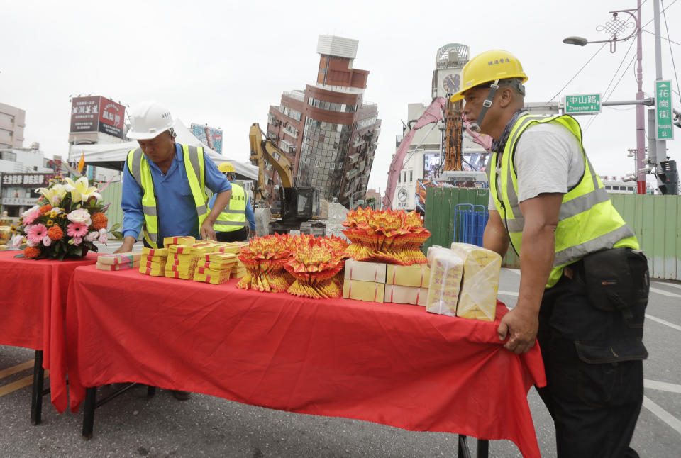 Workers set up offerings before the demolition ceremony in front of the building seen partially collapsed, two days after a powerful earthquake struck the city, in Hualien City, eastern Taiwan, Friday, April 5, 2024. (AP Photo/Chiang Ying-ying)