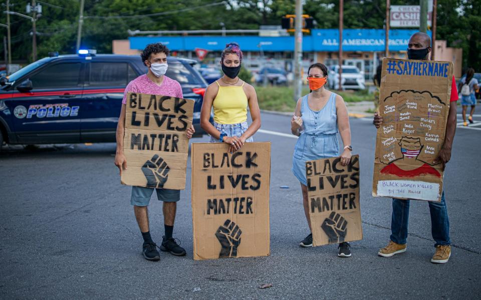 Protesters hold placards near the scene of an overnight police shooting which left a black man dead at a Wendy's restaurant in Atlanta, Georgia - ERIK S LESSER/EPA-EFE/Shutterstock