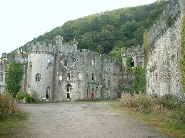 the exterior of gwrych castle with green hills in the background