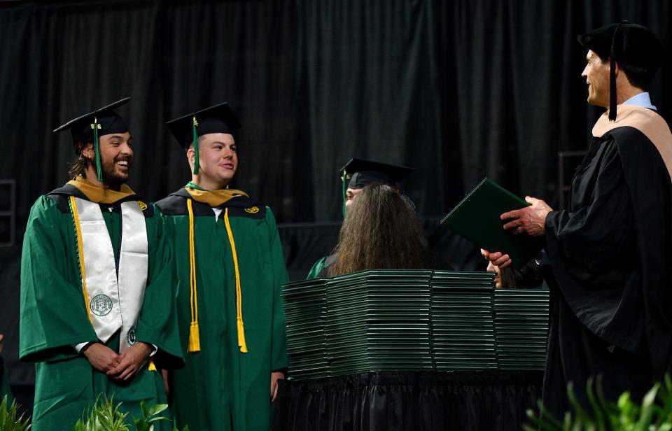 WORCESTER - Nichols College graduate Jarrod Sweeney, left, arrives on stage to find his father, Donald Sweeney, ready to present him with his diploma during commencement at the DCU Center on Saturday.