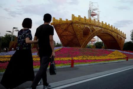 People walk past the installation "Golden Bridge on Silk Road" by artist Shuyong set up ahead of the Belt and Road Forum in Beijing, China May 10, 2017. REUTERS/Thomas Peter