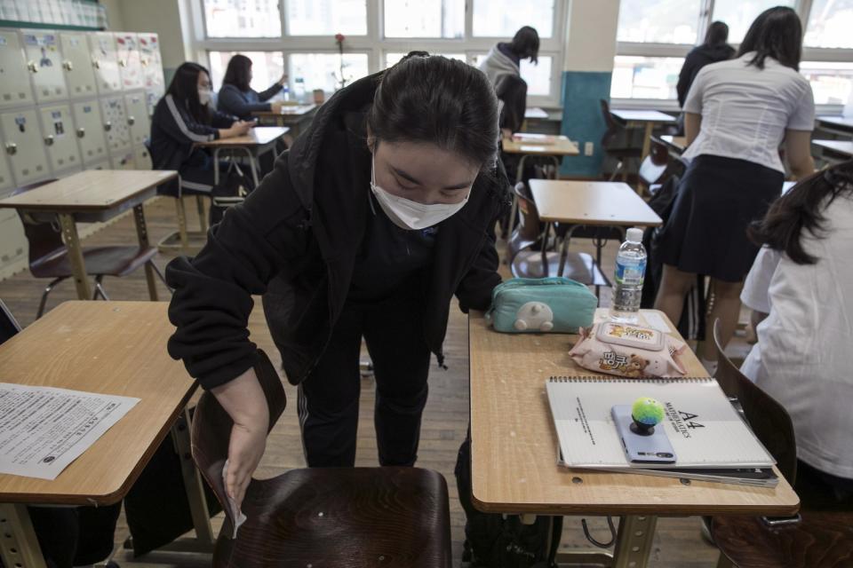 Students at Gyungbuk Girls' High School clean their personal space before class on the first day of school in Daegu, South Korea, on May 20, 2020.