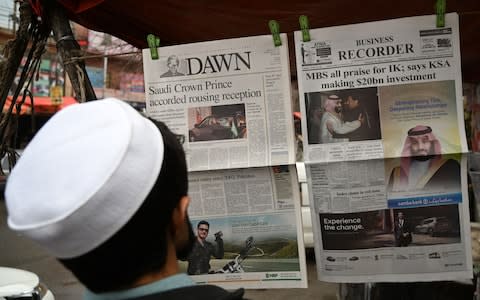 A Pakistani man looks at morning newspapers with front-page-coverage of MBS' visit - Credit: AFP