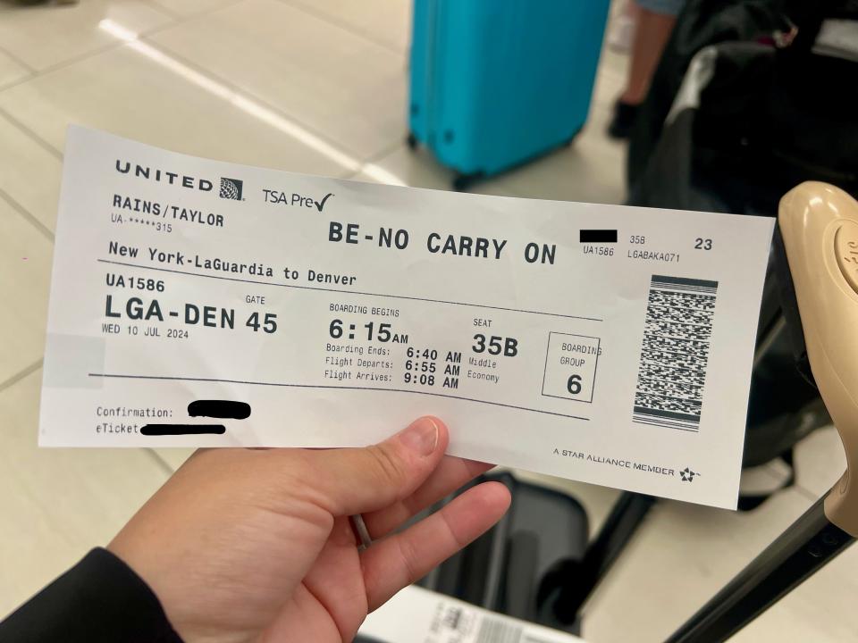 The author is holding a boarding pass with the flight information and "no carry-on" written in big letters across the top.