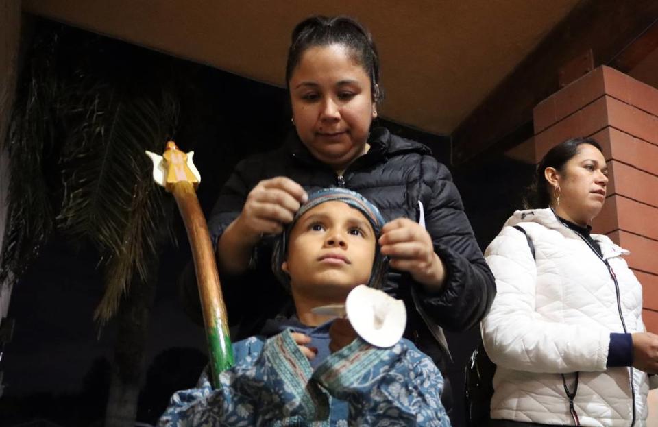 Una madre ajusta un vendaje para la cabeza de su hijo que participó en la posada organizada por la Iglesia de San Antonio María Claret en el sureste de Fresno, el 18 de diciembre de 2023.