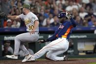 Houston Astros' Yordan Alvarez, right, scores as Oakland Athletics relief pitcher Sam Moll (60) covers home plate after throwing a wild pitch during the sixth inning of a baseball game Sunday, May 21, 2023, in Houston. (AP Photo/David J. Phillip)