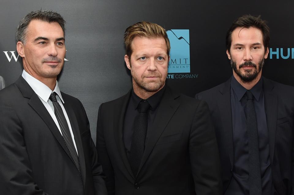 Chad Stahelski, David Leitch and Keanu Reeves in black suits standing next to each other