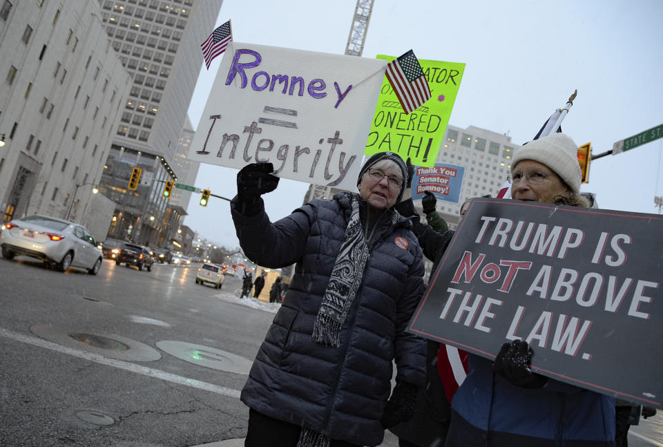 Larry Castle-Fericks, center, and Sue Corth, at right, show their support of Sen. Mitt Romney, R-Utah, at the Wallace F. Bennett Federal Building in Salt Lake City on Wednesday, Feb. 5, 2020. Republicans in the state are unusually divided on the president, so while some were heartened to see Romney cast what he described as an agonizing vote dictated by his conscience, Trump supporters were left angry and frustrated. (Francisco Kjolseth/The Salt Lake Tribune via AP)
