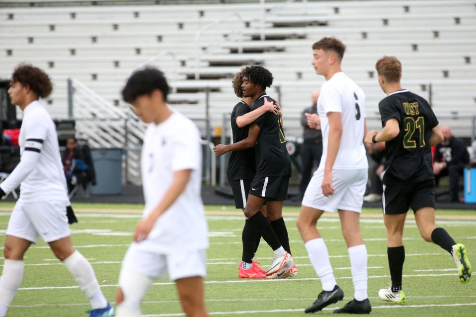 Iowa City West’s Kaleab Wendy (12) hugs teammate Liam Teghanemt after scoring a goal against Waterloo West on Thursday.