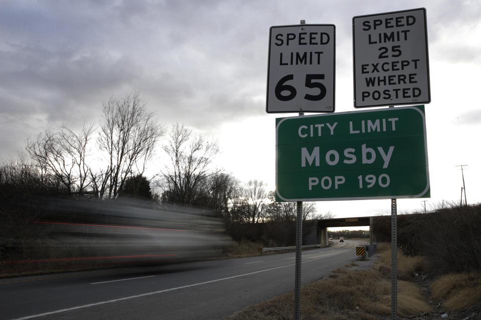 In this photo taken Monday, Nov. 18, 2019, vehicles pass by Mosby, Mo. About half the homes in the flood-prone town are being demolished as part of a voluntary buyout program. (AP Photo/Charlie Riedel)