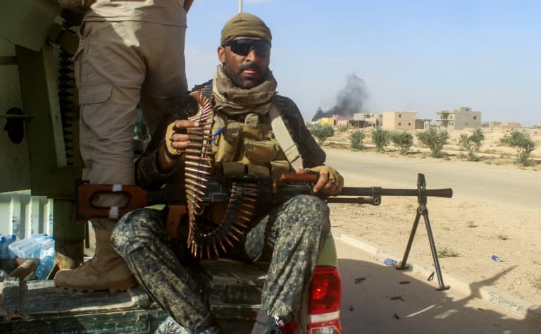 A member of the Iraqi forces carries a machine gun in a pickup truck during an operation to retake the town of Rawa from the Islamic State group on November 17, 2017