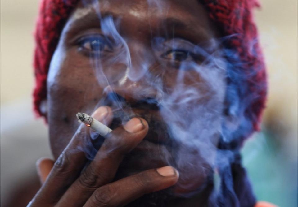 A man smokes tobacco at the opening of the marketing season at the Tobacco Sales Floor in Harare.
