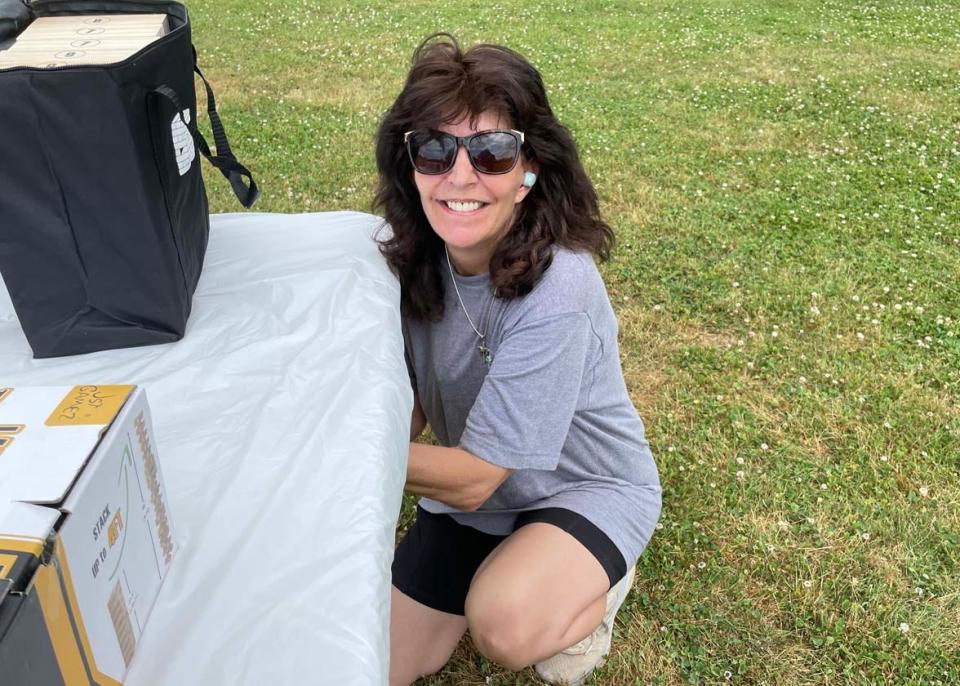 Candy Moran with Knox County Parks and Rec secures a table from the wind at the first Spring Lawn Games Festival held at Carl Cowan Park Sunday, May 22, 2022.