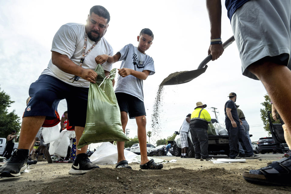 From left; David Rivera makes sandbags with his sons, Zack, 10, center, and Vincent, 18, at Wildwood Park in San Bernardino, Ca., on Saturday, Aug. 19, 2023, as residents gear up for the arrival of Hurricane Hilary. (Watchara Phomicinda/The Orange County Register via AP)