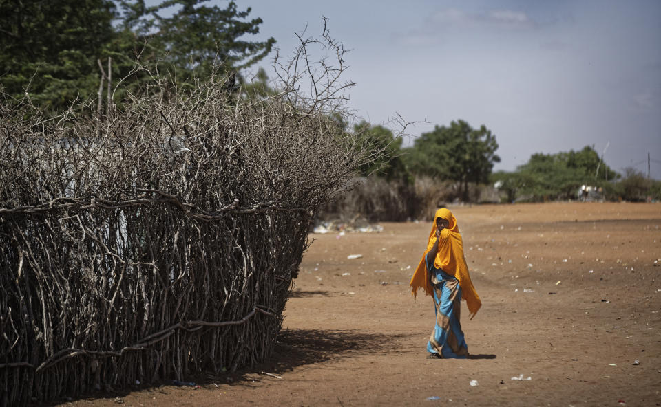 FILE - In this Tuesday, Dec. 19, 2017 file photo, a Somali refugee girl walks past the fence surrounding a hut at Dadaab refugee camp, hosting over 230,000 inhabitants, in northern Kenya. An internal United Nations document obtained by The Associated Press on Friday, March 29, 2019 says Kenya again seeks to close the Dadaab camp that hosts more than 200,000 refugees from neighboring Somalia. (AP Photo/Ben Curtis, File)