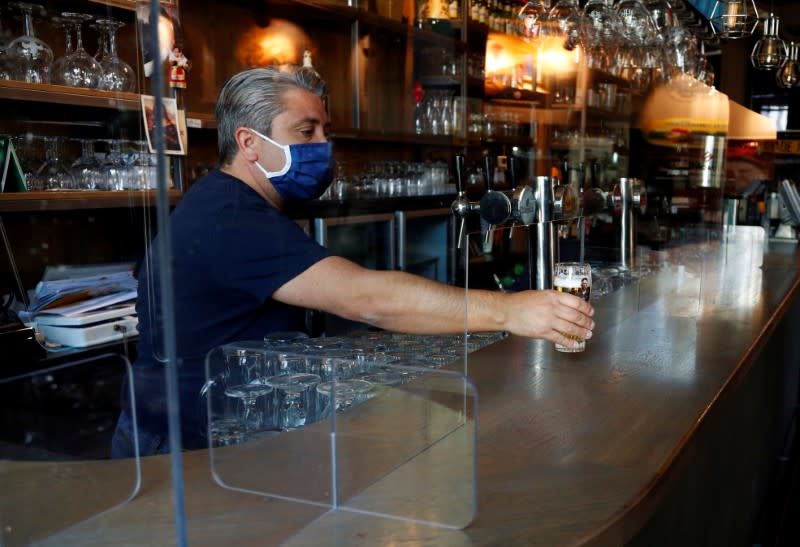 Bar owner tests a protective plexiglass screen amid the coronavirus disease (COVID-19) outbreak in Brussels