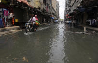 A motorcyclist drives through a street flooded by heavy rainfall in Karachi, Pakistan, Sunday, Aug. 9, 2020. Three days of heavy monsoon rains triggering flash floods killed at least dozens people in various parts of Pakistan, as troops with boats rushed to a flood-affected district in the country's southern Sindh province Sunday to evacuate people to safer places. (AP Photo/Fareed Khan)