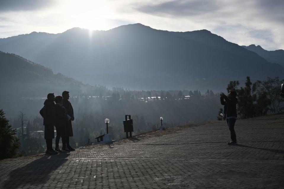 This photo taken on Dec. 7, 2019 shows tourists taking pictures with Bhutanese tour guides in Punakha province in Bhutan.<span class="copyright">LILLIAN SUWANRUMPHA/AFP via Getty Images</span>