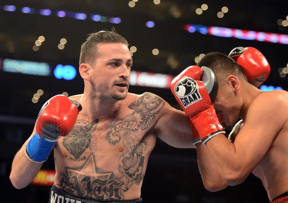 One boxer is seen aiming a swing at another boxer, who is seen blocking his face.