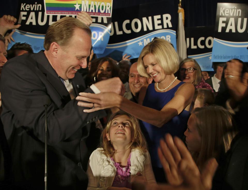 San Diego mayoral candidate Kevin Faulconer reaches for his wife, Katherine, as their daughter looks up from below after Faulconer addressed his supporters at a rally Tuesday, Feb. 11, 2014, in San Diego. (AP Photo/Lenny Ignelzi)