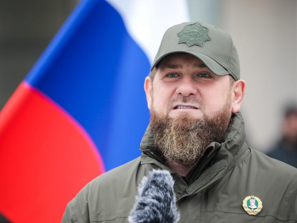 Chechen leader Ramzan Kadyrov at a microphone in front of a Russian flag.