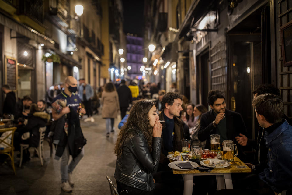 Tourists and locals have drinks at a bar in downtown Madrid, Spain, Friday, March 26, 2021. With its policy of open bars and restaurants — indoors and outdoors — and by keeping museums and theaters running even when outbreaks have strained hospitals, Madrid has built a reputation as an oasis of fun in Europe’s desert of restrictions. Other Spanish regions have a stricter approach to entertainment. Even sunny coastal resorts offer a limited range of options for the few visitors that started to arrive, coinciding with Easter week, amid a set of contradictory European travel rules. (AP Photo/Bernat Armangue)