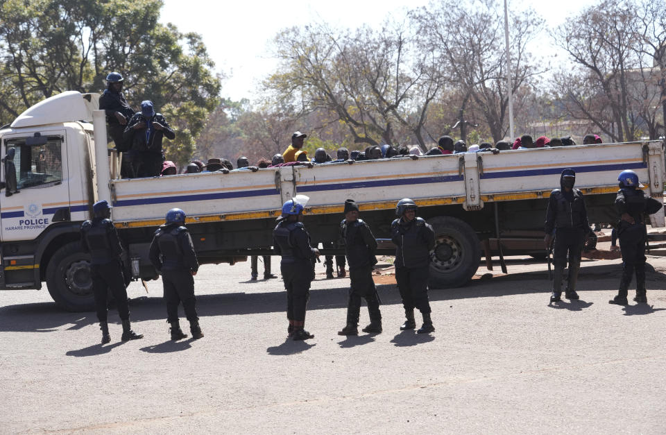 FILE - Riot place surround a truck with opposition supporters before their court appearance at the magistrates courts in Harare, Thursday, Aug, 17 2023. More than a dozen opposition figures including elected representatives, officials and activists have been targeted with violence or arrested by police in Zimbabwe. Many had hoped for a post-election rapprochement that is badly needed in the once prosperous southern African country. (AP Photo/Tsvangirayi Mukwazhi)