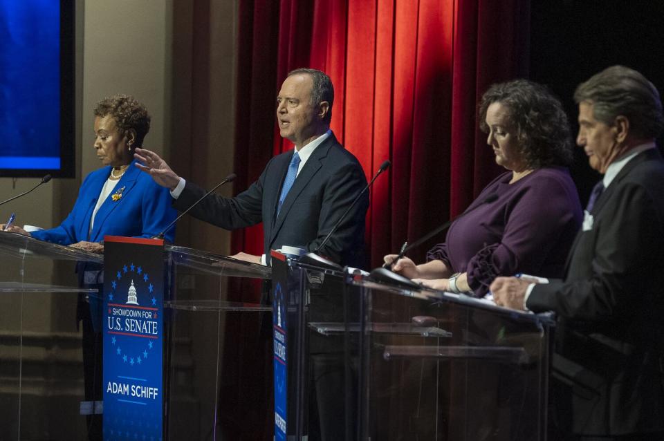 Adam Schiff gestures while speaking as Barbara Lee, Katie Porter and Steve Garvey listen, all standing at lecterns onstage