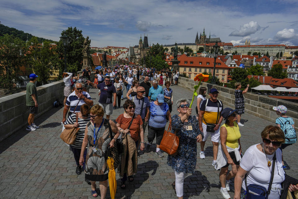 A pack of tourists walk during a guided tour in Prague, Czech Republic, Wednesday, July 5, 2023. Crowds are packing the Colosseum, the Louvre, the Acropolis and other major attractions as tourism exceeds 2019 records in some of Europe’s most popular destinations. While European tourists helped the industry on the road to recovery last year, the upswing this summer is led largely by Americans, who are lifted by a strong dollar and in some cases pandemic savings. (AP Photo/Petr David Josek)