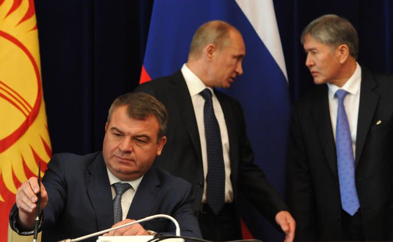 Then-Russian defence minister Anatoly Serdyukov (left) signs a document as President Vladimir Putin (centre) and his Kyrgyz counterpart Almazbek Atambayev (right) speak at Atambayev's residence near Bishkek on September 20, 2012. Russian investigators said Friday they may press charges against Serdyukov after he refused to answer questions about his alleged role in an illegal property scheme