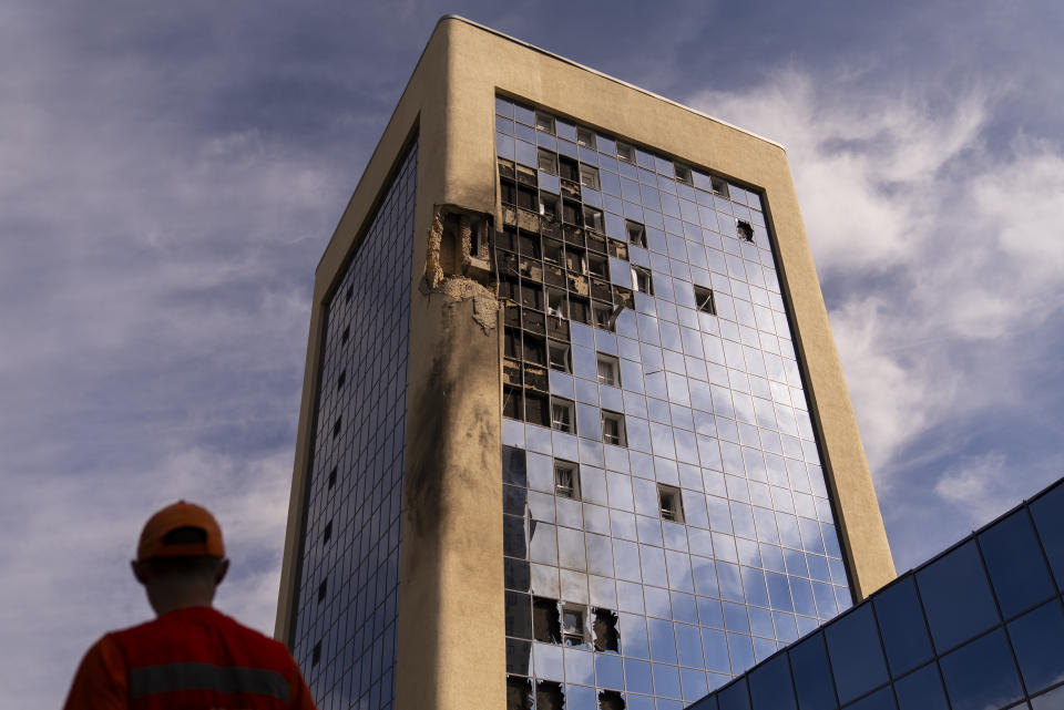 A maintenance worker stands outside a damaged government building in Kyiv, Ukraine, Wednesday, Aug. 2, 2023, following Russian drone attacks. (AP Photo/Jae C. Hong)