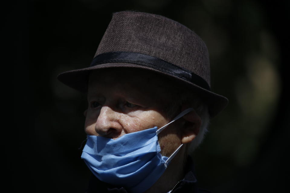 Holocaust survivor Shalom Stamberg wears a mask and keeps a safe distance from others while attending an annual Holocaust memorial ceremony held outside this year because of the coronavirus, in the northern Israeli city of Haifa, Israel, Tuesday, April 21, 2020. (AP Photo/Ariel Schalit)