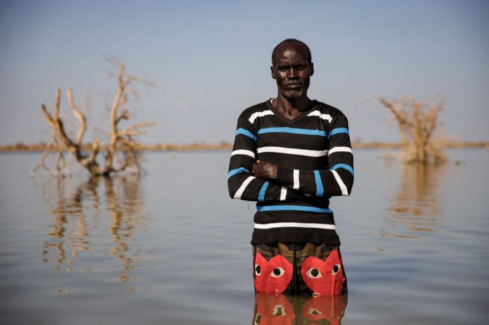 A man poses for a portrait on flooded land.