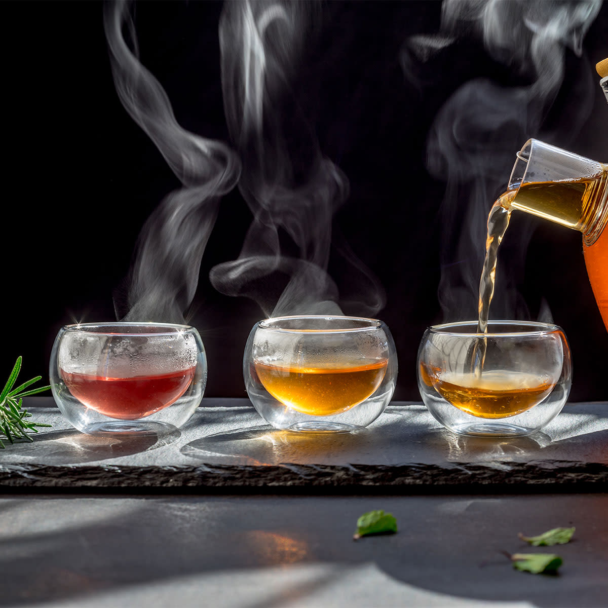 three glass cups of herbal tea being poured