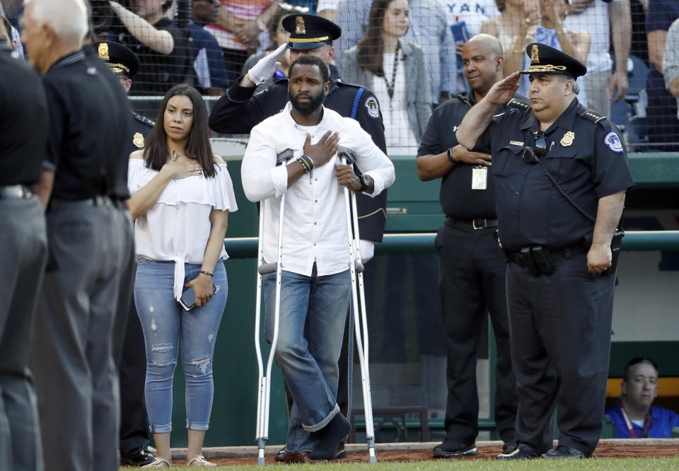 <p>Injured Capitol Hill Police officer David Bailey, center, holds his hand over his heart during the National Anthem with U.S. Capitol Police Chief Matthew Verderosa, far right, before the Congressional baseball game, Thursday, June 15, 2017, in Washington. The annual GOP-Democrats baseball game raises money for charity. (Photo: Alex Brandon/AP) </p>