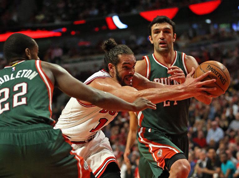 Chicago Bulls' Joakim Noah drives between Milwaukee Bucks' Khris Middleton (L) and Zaza Pachulia during the first round of the NBA Playoffs at the United Center on April 20, 2015