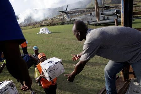 Haitians load supplies delivered by a Marines helicopter after Hurricane Matthew in Les Anglais, Haiti, October 11, 2016. REUTERS/Andres Martinez Casares