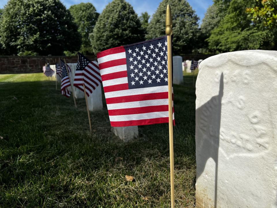 Volunteers place flags on graves at  Alexandria National Cemetery Saturday.