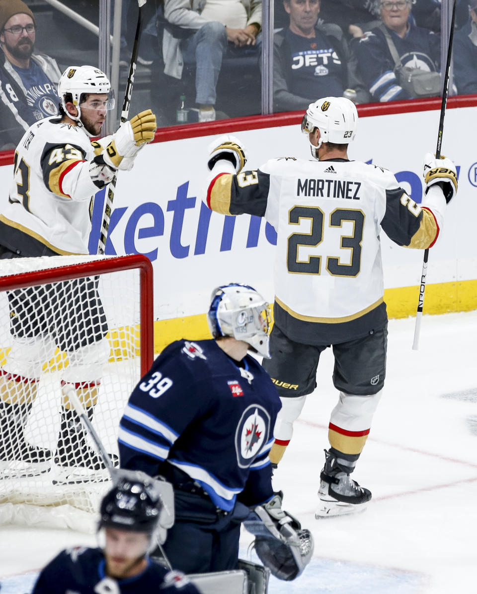 Vegas Golden Knights' Paul Cotter (43) and Alec Martinez (23) celebrate after Martinez's goal against Winnipeg Jets goaltender Laurent Brossoit (39) during second-period NHL hockey game action in Winnipeg, Manitoba, Thursday, Oct. 19, 2023. (John Woods/The Canadian Press via AP)