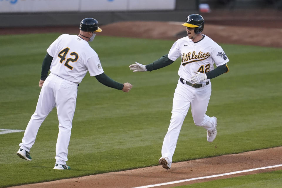 Oakland Athletics' Stephen Piscotty, right, is congratulated by third base coach Mark Kotsay after hitting a solo home run against the Detroit Tigers during the third inning of a baseball game in Oakland, Calif., Thursday, April 15, 2021. (AP Photo/Jeff Chiu)