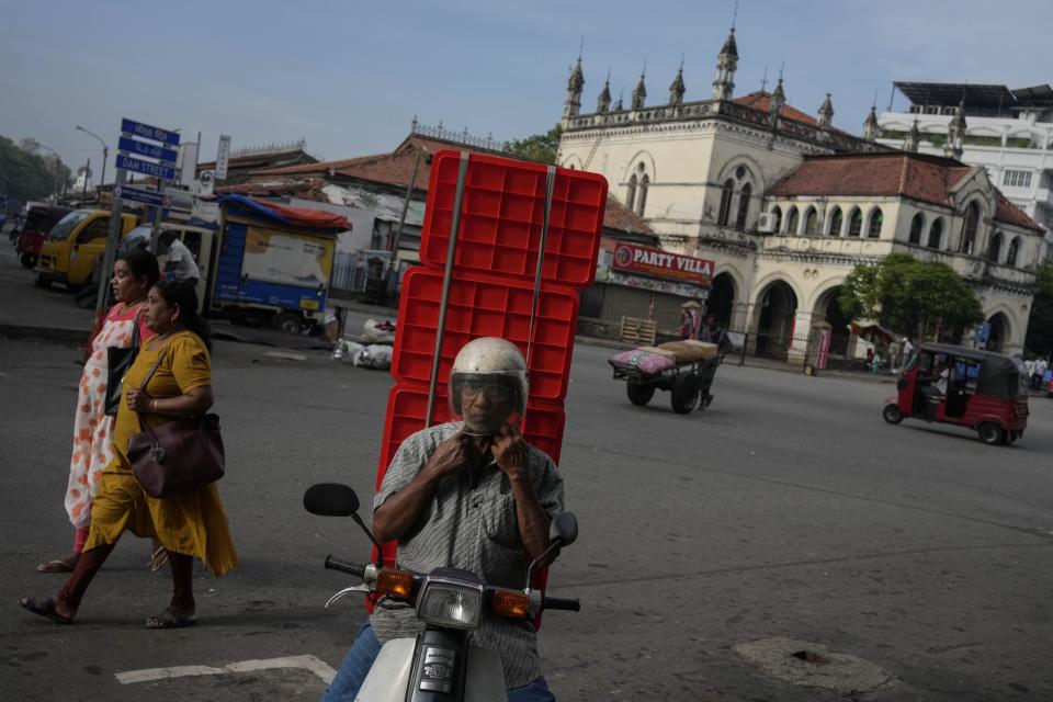 A Sri Lankan trader arrives at a market place for business in the morning in Colombo, Sri Lanka, Tuesday, March 21, 2023. The International Monetary Fund said Monday that its executive board has approved a nearly $3 billion bailout program for Sri Lanka over four years to help salvage the country's bankrupt economy.(AP Photo/Eranga Jayawardena)